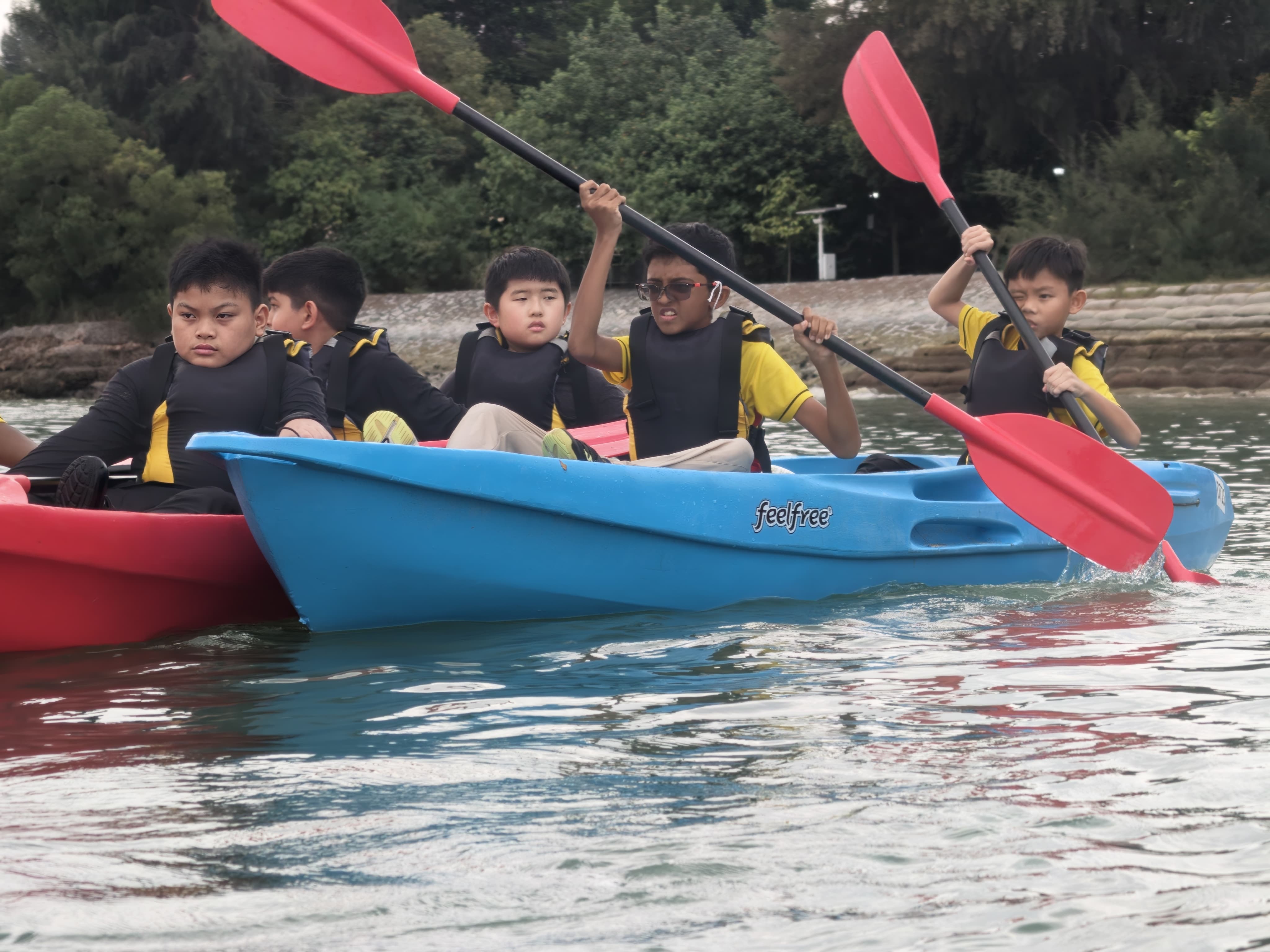 Students work together to paddle their boats